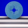 Blue abrasive disc on metal rods, blue background.