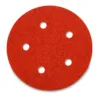 Red circular sanding disc with six holes.