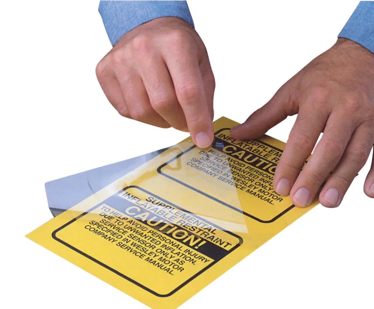 Person applying protective film on caution label.