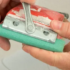 Hand using sanding block on surface