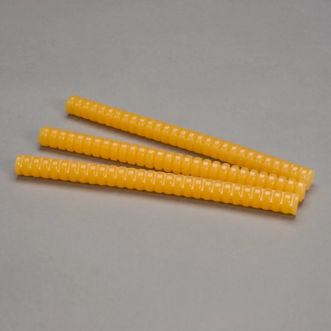 Four yellow ribbed plastic dowels on gray background.