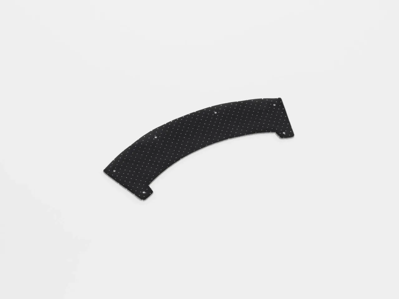 Curved perforated black plastic piece on white background.